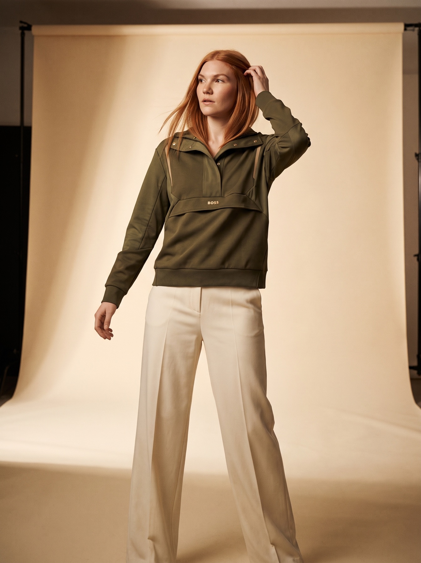 Modelo generada con IA con un saco verde y pantalón crema en una foto de campaña de estudio